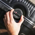 Na zbliżeniu dłoń zamyka walizkę za pomocą zamka szyfrowego, co podkreśla bezpieczeństwo.