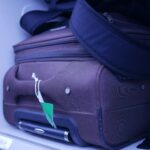 Zbliżenie na bagaż w schowku nad głową samolotu, przedstawiające niezbędne akcesoria podróżne.