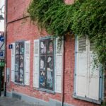 Mur ceglany z bluszczem i artystycznym wystrojem okien na ulicy w Brukseli.