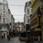 Bruksela - serce Unii Europejskiej: jak zwiedzać europejskie instytucje i co warto wiedzieć o stolicy Belgii Urocza brukowana ulica w Brukseli z kawiarniami i klasyczną architekturą.