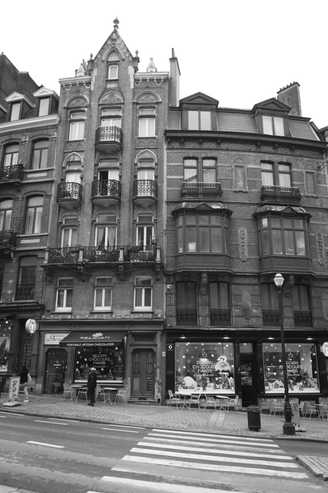 belgia Czarno-białe zdjęcie klasycznej europejskiej ulicy z zabytkową architekturą i kawiarnią na świeżym powietrzu.