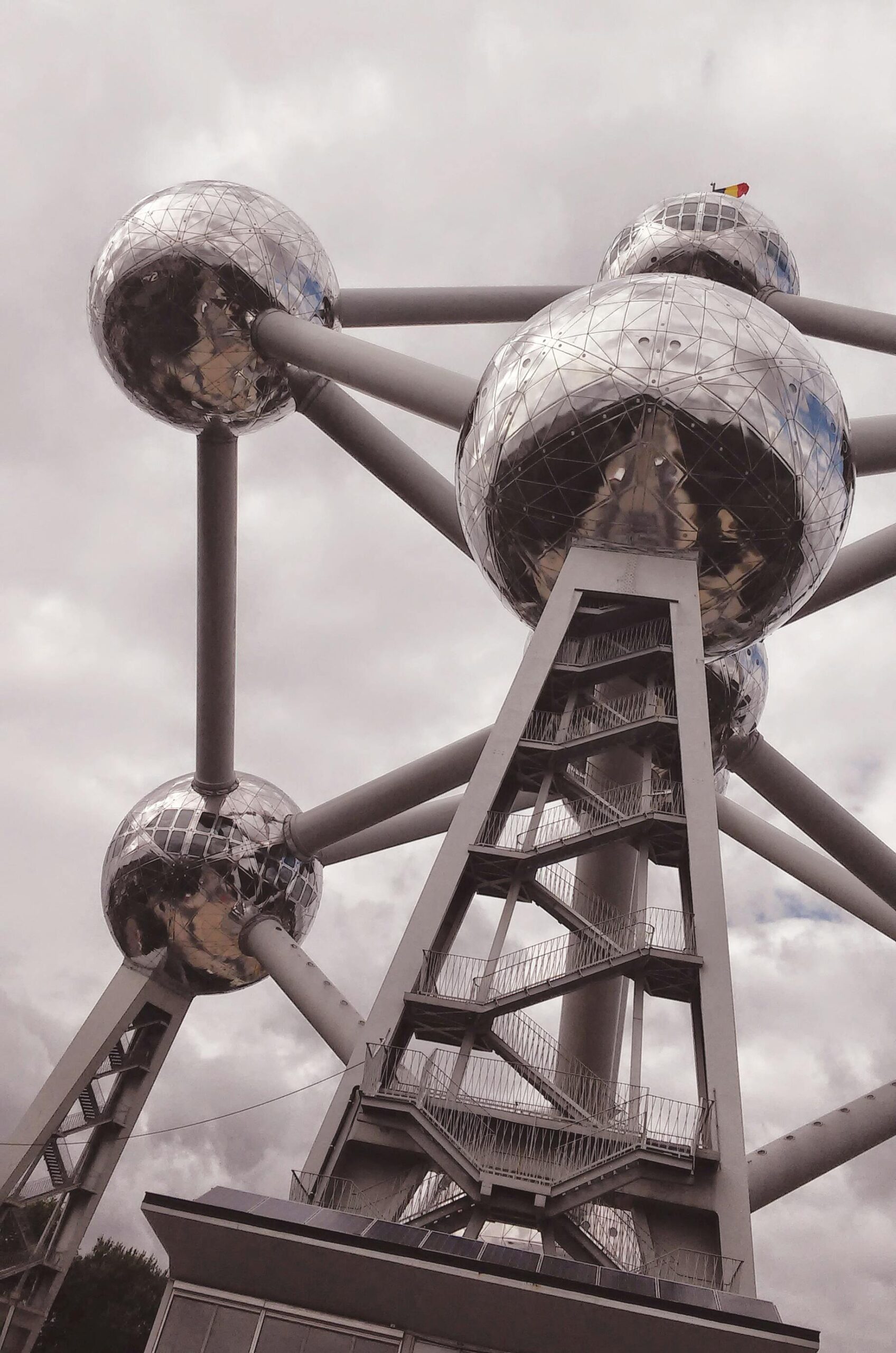 Zbliżenie struktury Atomium w Brukseli z dramatycznym pochmurnym niebem.