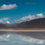 Dwie osoby spacerują po słynnych równinach solnych Uyuni, skąd roztaczają się wspaniałe widoki na góry pod czystym, błękitnym niebem.