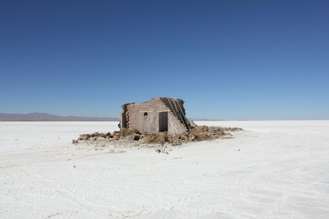 Opuszczona konstrukcja na opuszczonych i suchych równinach solnych pod czystym, błękitnym niebem.