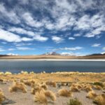 Amazonka w Boliwii – Niezapomniana podróż do Parku Madidi Zapierający dech w piersiach widok na Altiplano z spokojnym jeziorem i ośnieżonymi Andami pod czystym niebem.