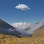 Zapierający dech w piersiach widok na pojedynczą chmurę unoszącą się nad górską doliną w Boliwii pod błękitnym niebem.