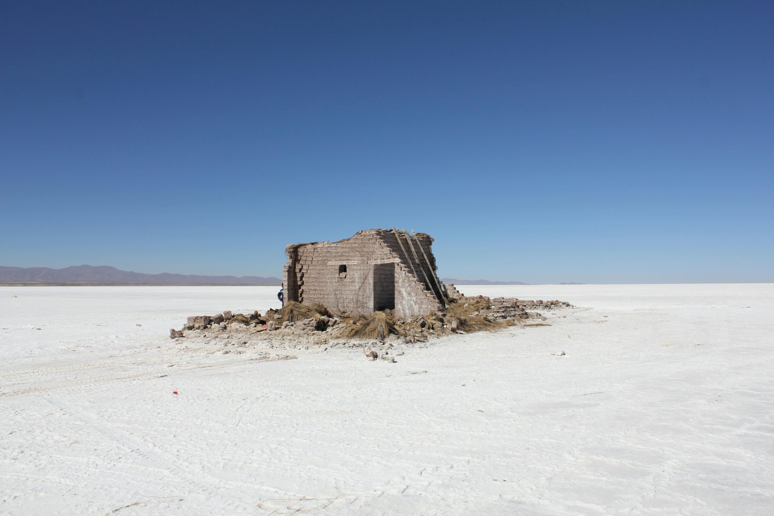 Opuszczona konstrukcja na opuszczonych i suchych równinach solnych pod czystym, błękitnym niebem.