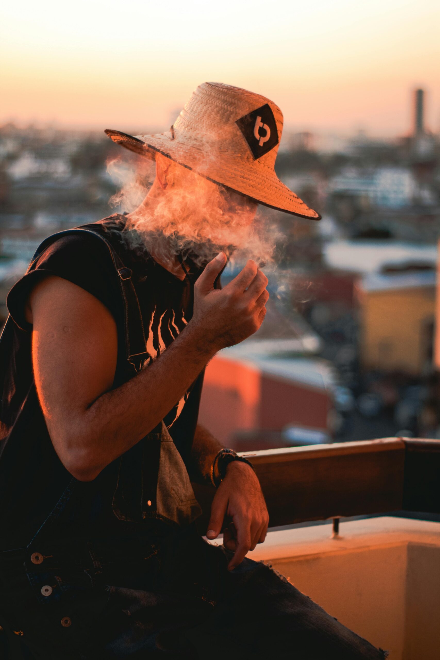 Mężczyzna w słomkowym kapeluszu pali na balkonie w Santa Cruz de la Sierra o zachodzie słońca.