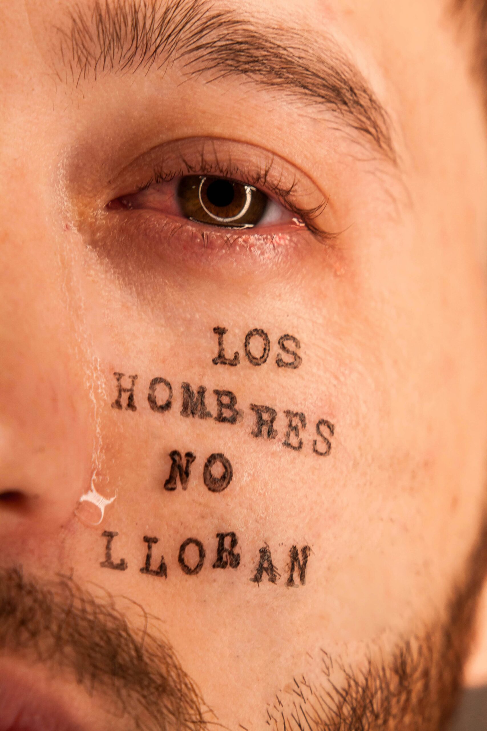 Emocjonalne zbliżenie oka mężczyzny ze łzą i wytatuowanym przesłaniem.