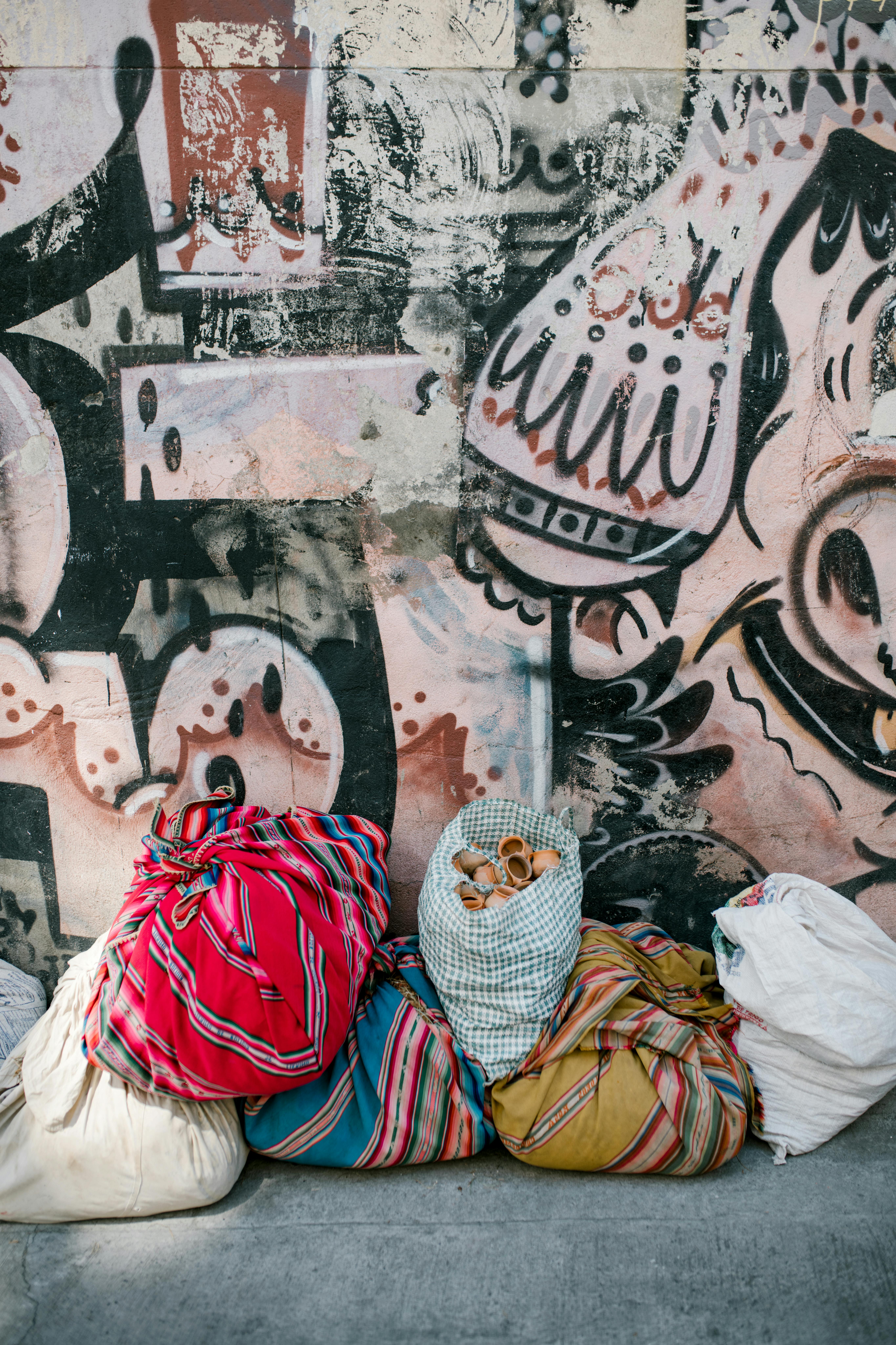 Worki z kolorowymi wzorami na tle tętniącej życiem ściany graffiti w La Paz w Boliwii.