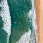 Kuchnia brazylijska: Najlepsze dania i gdzie ich spróbować Odkryj hipnotyzujący widok z lotu ptaka na plażę Florianópolis z falującymi falami i nieskazitelnym piaskiem.