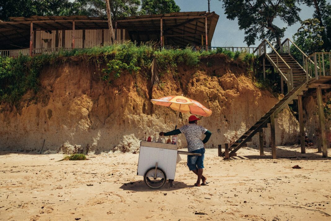 Sprzedawca plażowy z wózkiem z lodami pod parasolem na plaży Nazaré w Brazylii.