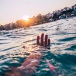 Dramatyczna scena oceaniczna z ręką w turkusowych wodach o zachodzie słońca w pobliżu Vila Nova w Brazylii.