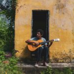 Belem: Brama do Amazonii i smakowity targ Ver-o-Peso Mężczyzna gra na gitarze przed rustykalnym żółtym domem w Brazylii, w słoneczny dzień.