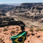 Kobieta trzyma brazylijską flagę na skraju wspaniałego Wielkiego Kanionu pod czystym niebem.