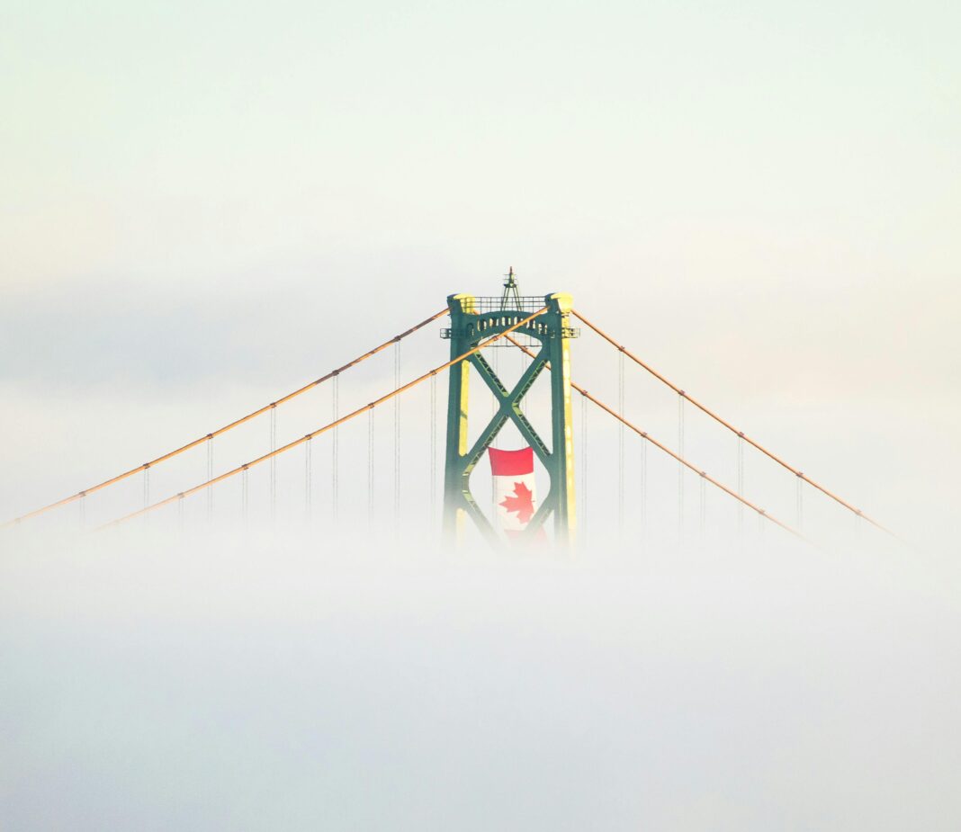 canada Słynny most wiszący w Halifax w Kanadzie, spowity mgłą, z wyraźną kanadyjską flagą.