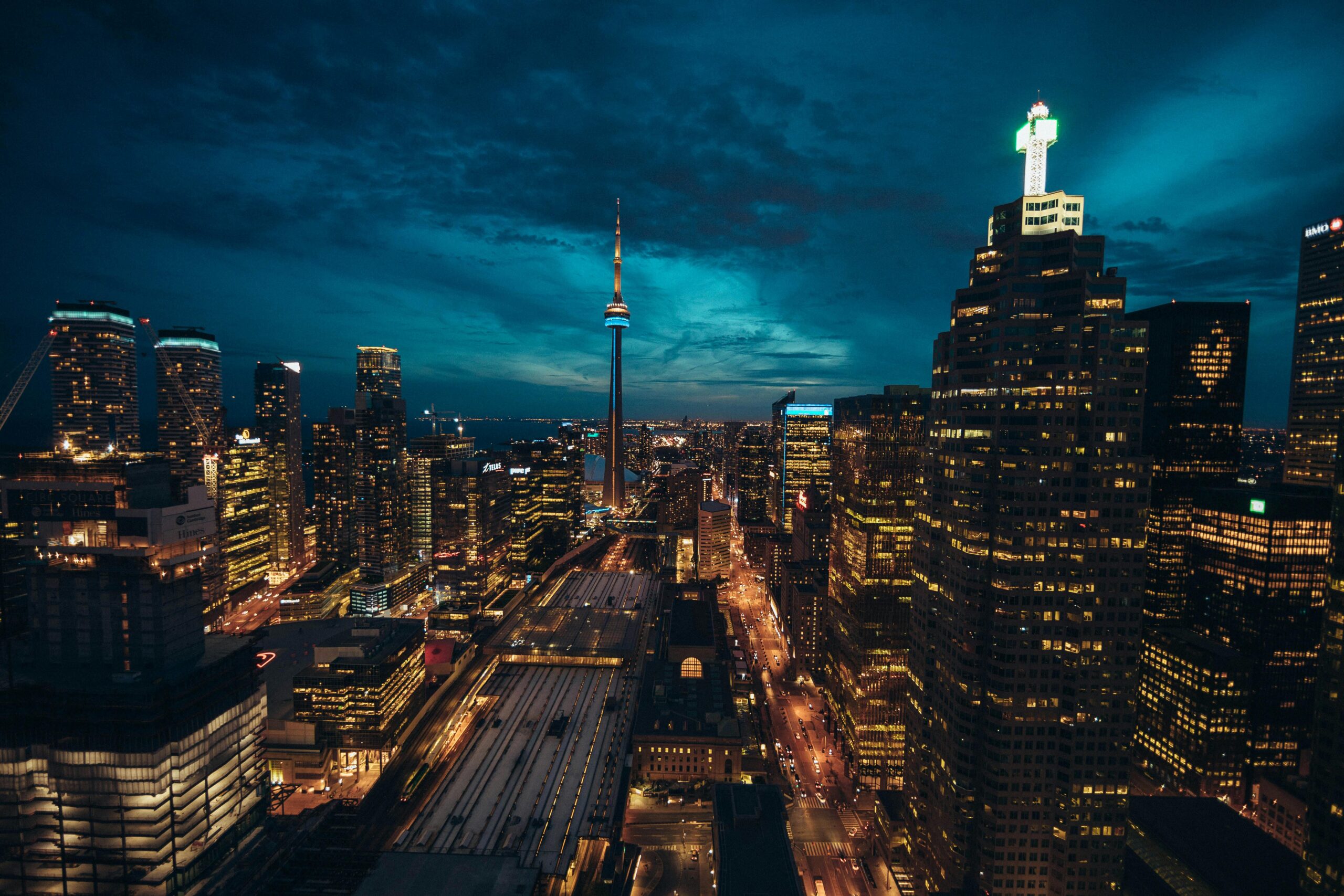 Oszałamiający pejzaż Toronto nocą z oświetloną wieżą CN i tętniącą życiem miejską panoramą.