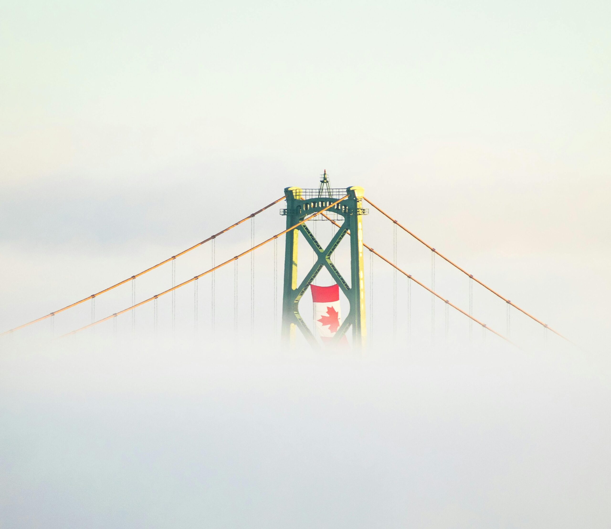 Słynny most wiszący w Halifax w Kanadzie, spowity mgłą, z wyraźną kanadyjską flagą.