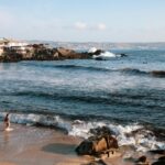 Spokojny widok na ocean z plaży Las Cruces w Chile, z falami i nadmorskimi domami.