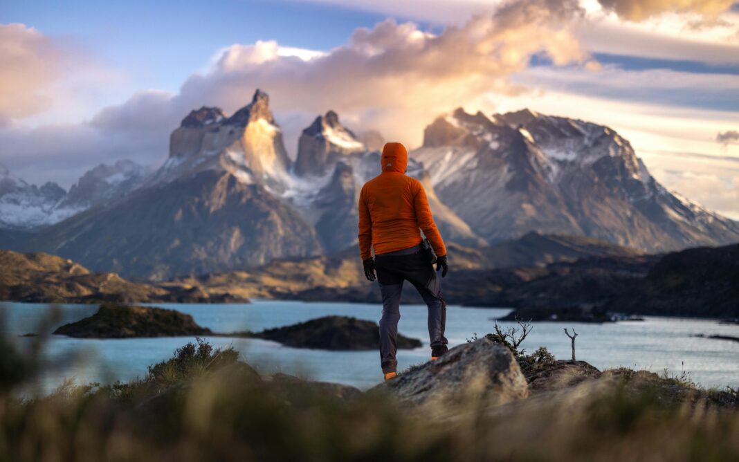 chile Turysta stoi o wschodzie słońca w Torres del Paine w Chile, z widokiem na majestatyczne góry i spokojne jezioro.