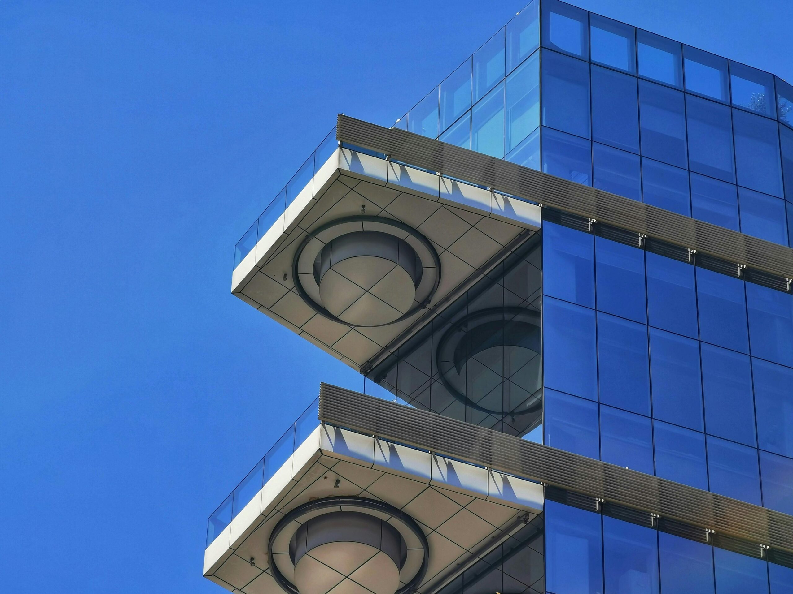 Zbliżenie na nowoczesną szklaną fasadę budynku w Santiago, przedstawiające projekt architektoniczny na tle czystego, błękitnego nieba.