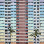 Żywa fasada budynku mieszkalnego w Hongkongu z palmami na pierwszym planie.