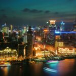 Zapierający dech w piersiach widok na oświetloną panoramę Szanghaju nocą nad nabrzeżem.