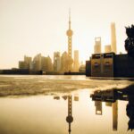 Oszałamiający widok na panoramę Szanghaju odbijającą się w kałuży podczas wschodu słońca, ukazującą architekturę miejską.