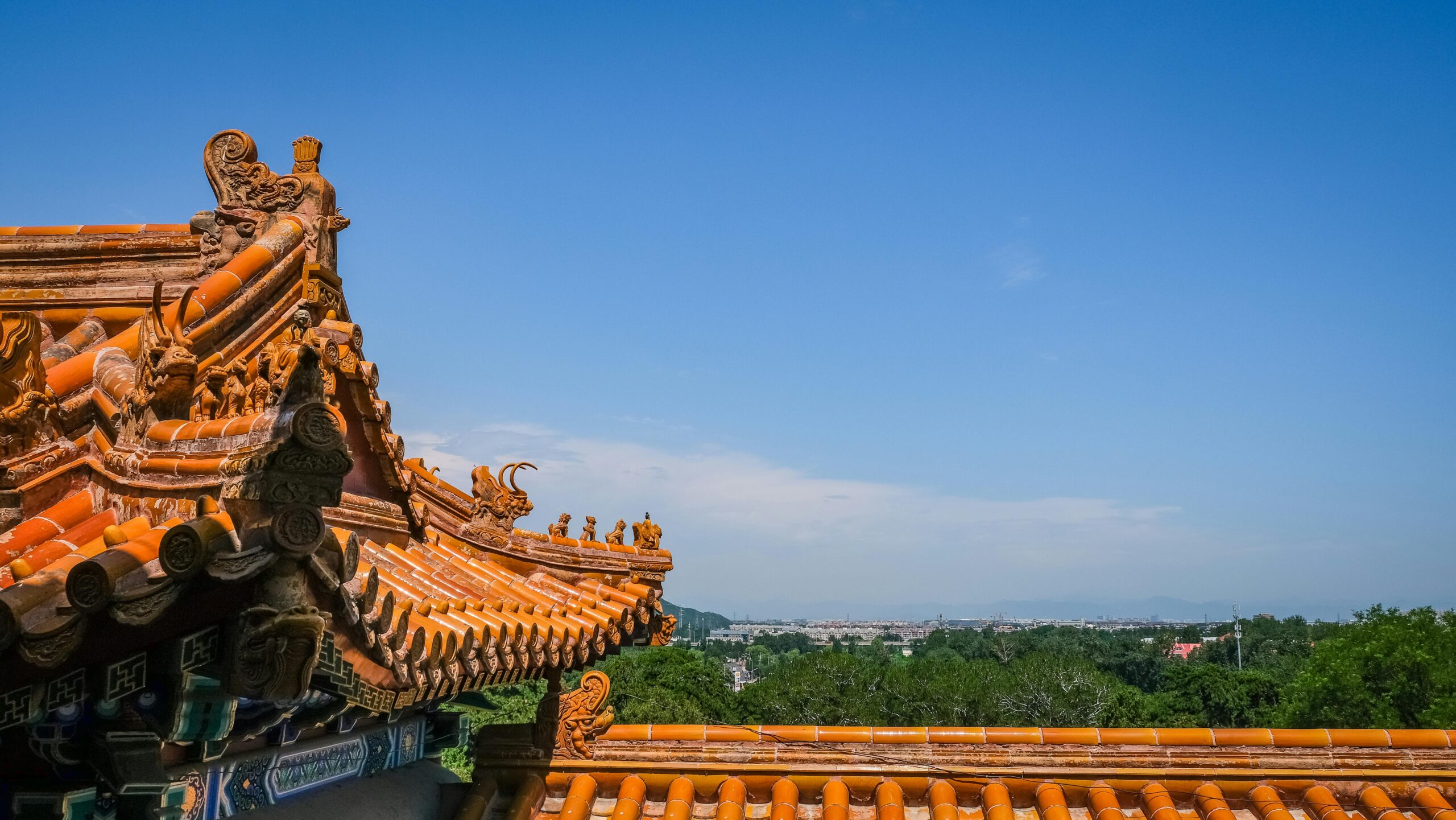 Tradycyjny chiński dach ze skomplikowanymi detalami na tle czystego, błękitnego nieba w Pekinie.