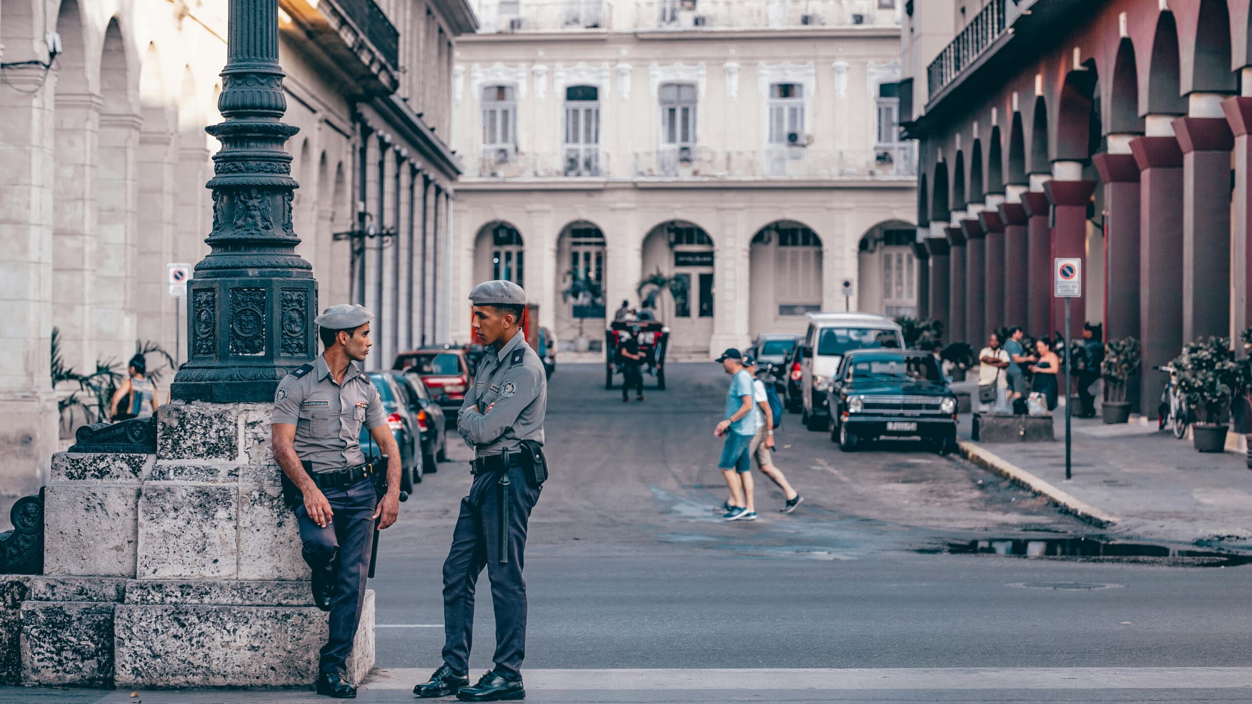 Policjanci rozmawiający na malowniczej ulicy w Hawanie, prezentującej zabytkową architekturę.