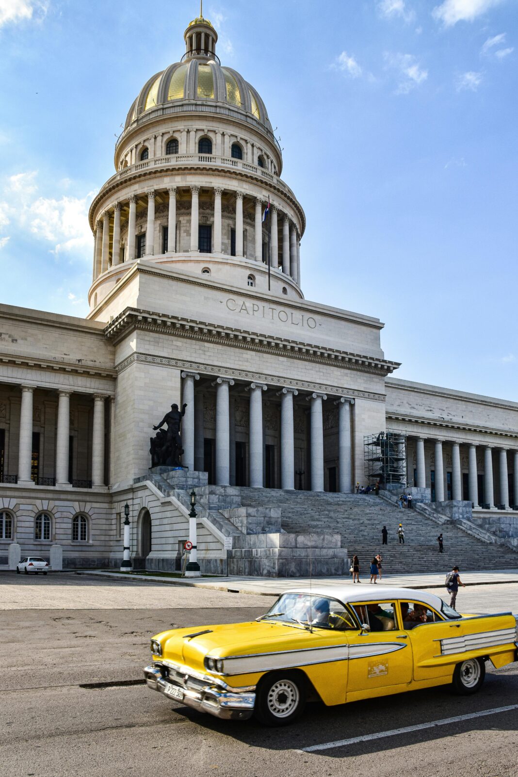 cuba Klasyczny żółty samochód przejeżdżający obok El Capitolio w Hawanie na Kubie, z czystym błękitnym niebem.