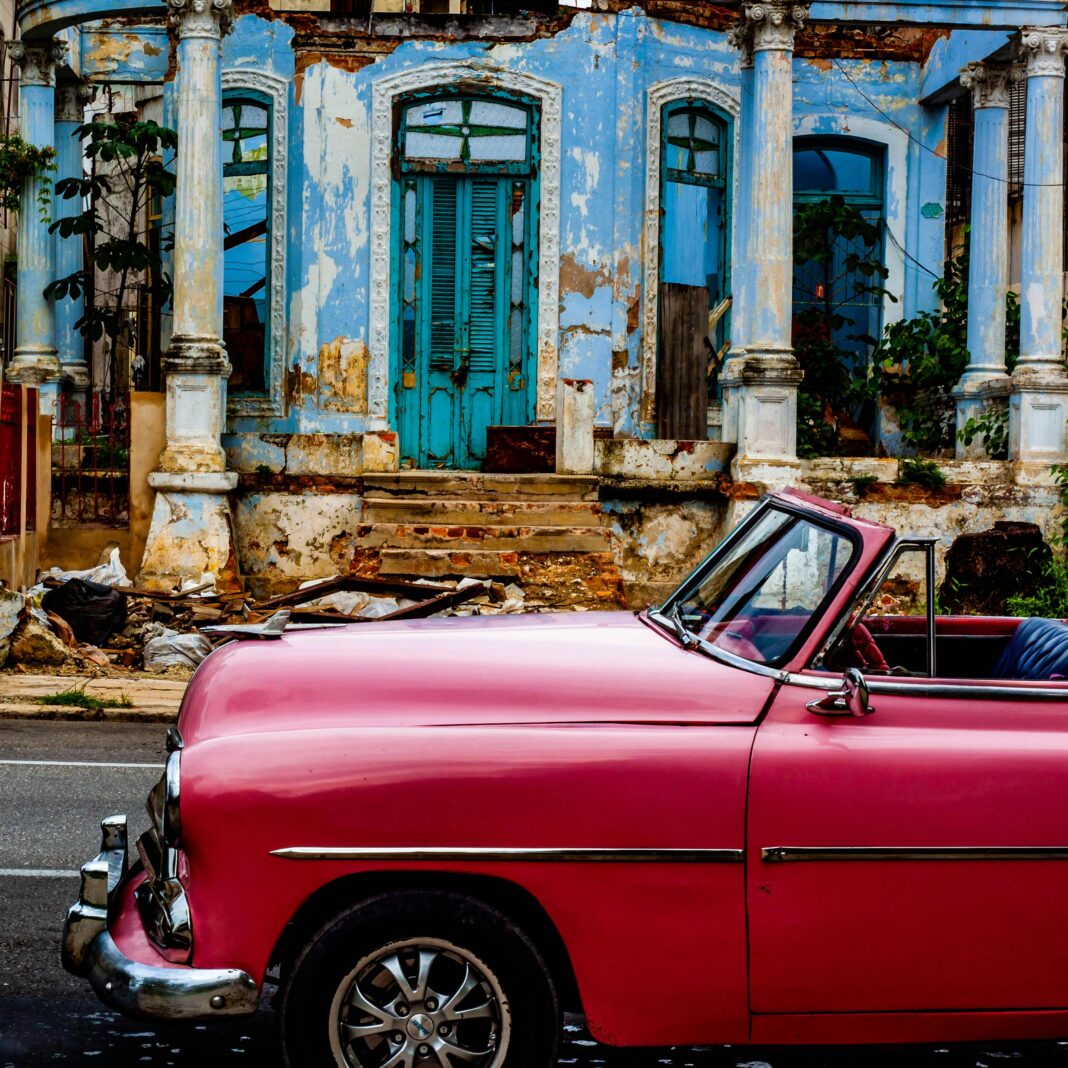cuba Klasyczny różowy samochód zaparkowany przy zniszczonym budynku w Hawanie, ukazujący nostalgiczny miejski urok.