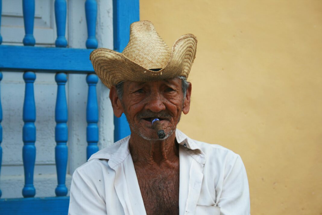 cuba Portret starszego mężczyzny z cygarem, w słomkowym kapeluszu na kolorowym tle.