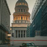 Dlaczego samochody na Kubie są tak wyjątkowe? Klasyczny zabytkowy samochód przed El Capitolio w Hawanie o zmierzchu z rusztowaniami na ulicy.