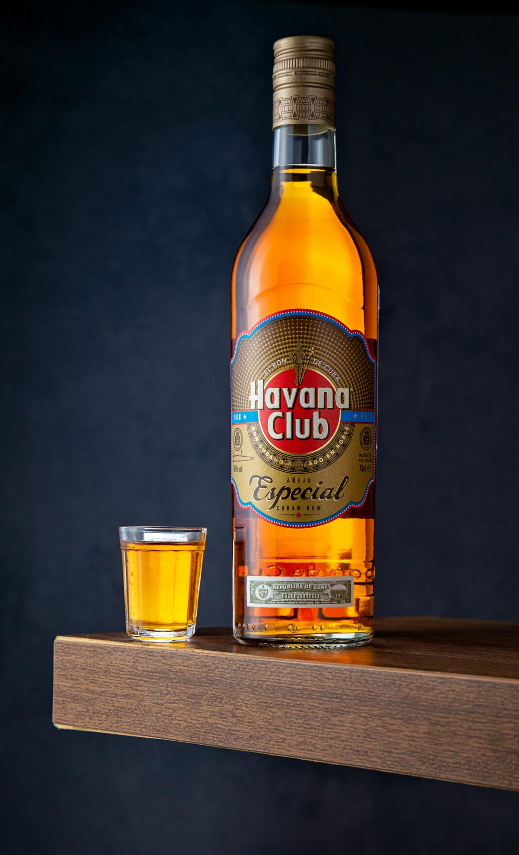 Zbliżenie: butelka rumu Havana Club z kieliszkiem na powierzchni drewnianej.