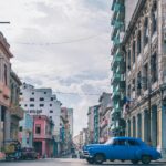 Urzekająca scena miejska w Hawanie z zabytkową architekturą i klasycznym niebieskim samochodem pod czystym niebem.