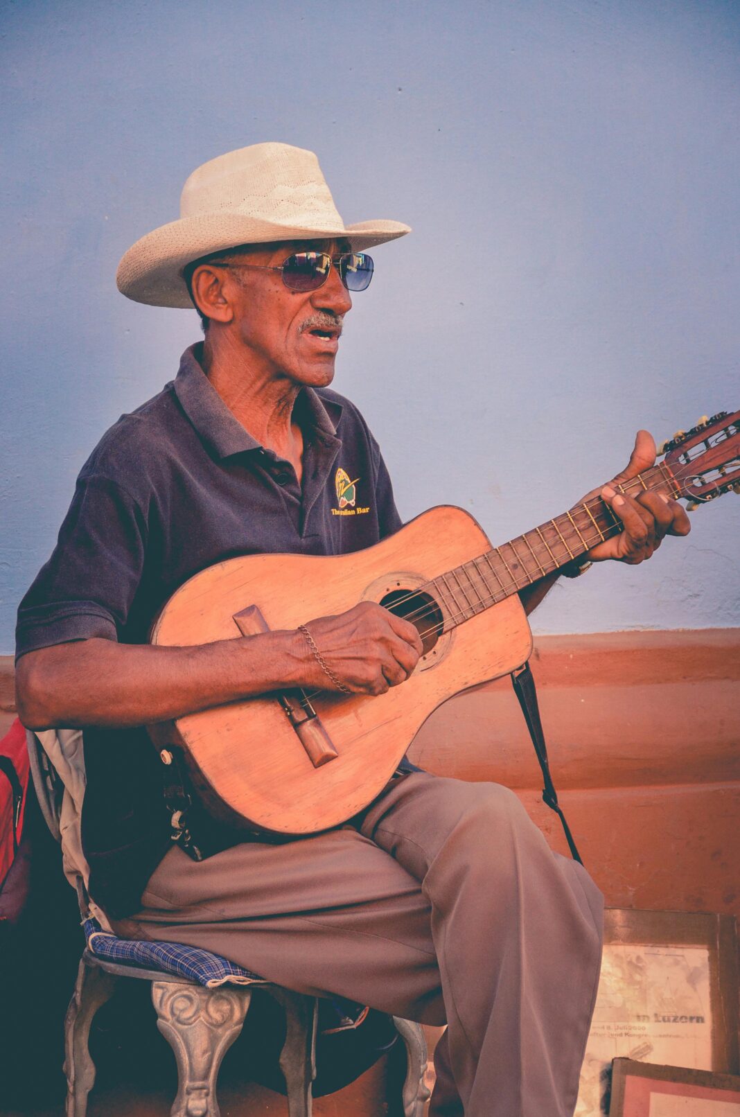 cuba Starszy muzyk występujący z gitarą na tętniącym życiem rogu ulicy, ubrany w tradycyjny kapelusz.