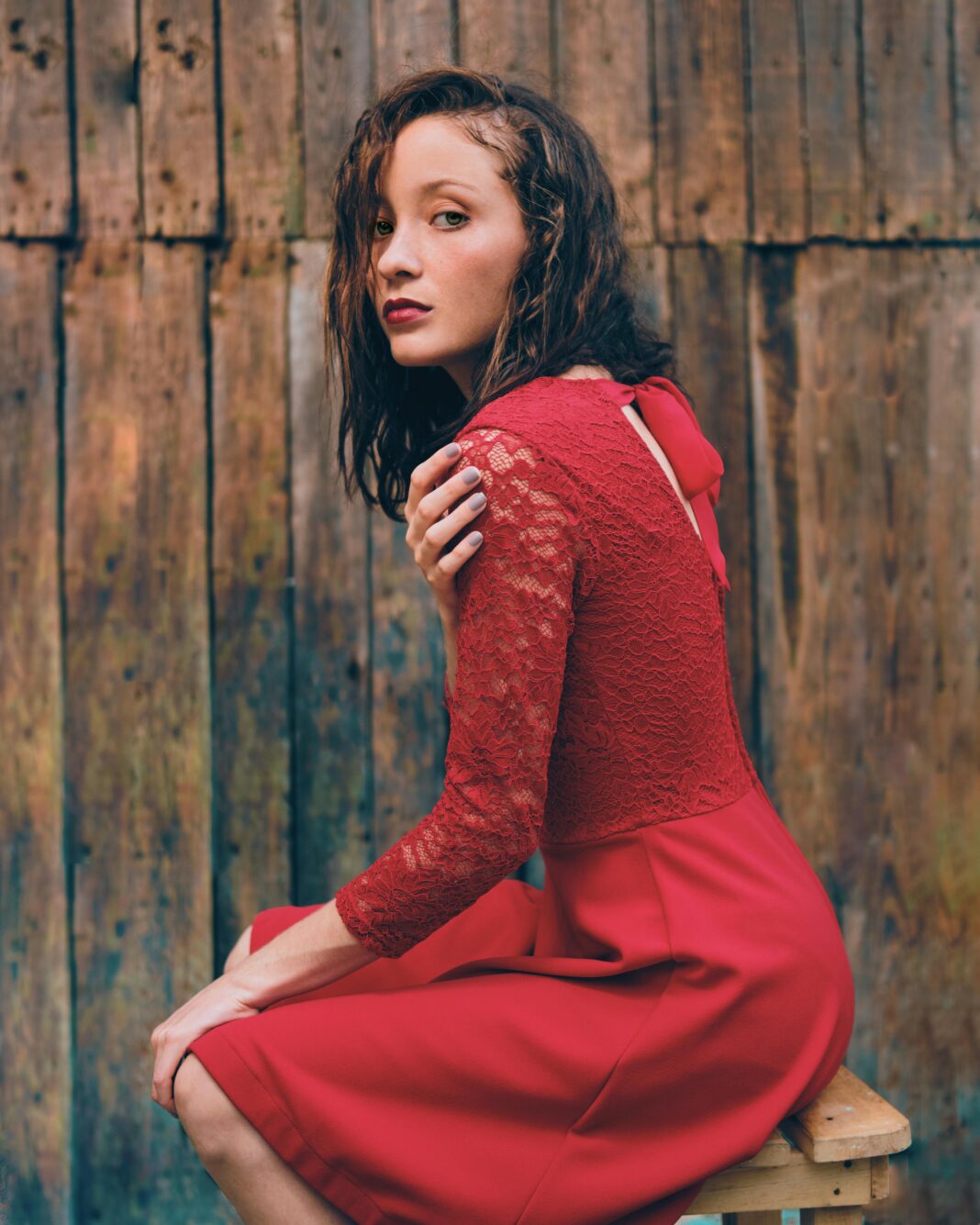 Modna kobieta w czerwonej sukience pozuje na rustykalnym drewnianym tle w Santa Cruz del Sur na Kubie.