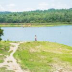 Fauna Kuby – krokodyle, iguany i kolibry Spokojna scena nad jeziorem z zielenią i samotną osobą spacerującą, uchwycona w Vinales na Kubie.