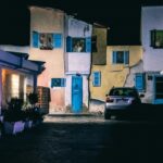 Niesamowita scena miejska z kolorowymi fasadami i zaparkowanym samochodem w nocy. 