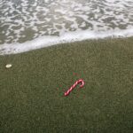 Zakupy na Cyprze: Skarby Wyspy Afrodyty, Które Zmieszczą się w Twojej Walizce Samotna laska cukrowa leży na piaszczystej plaży z delikatnymi falami na Cyprze.