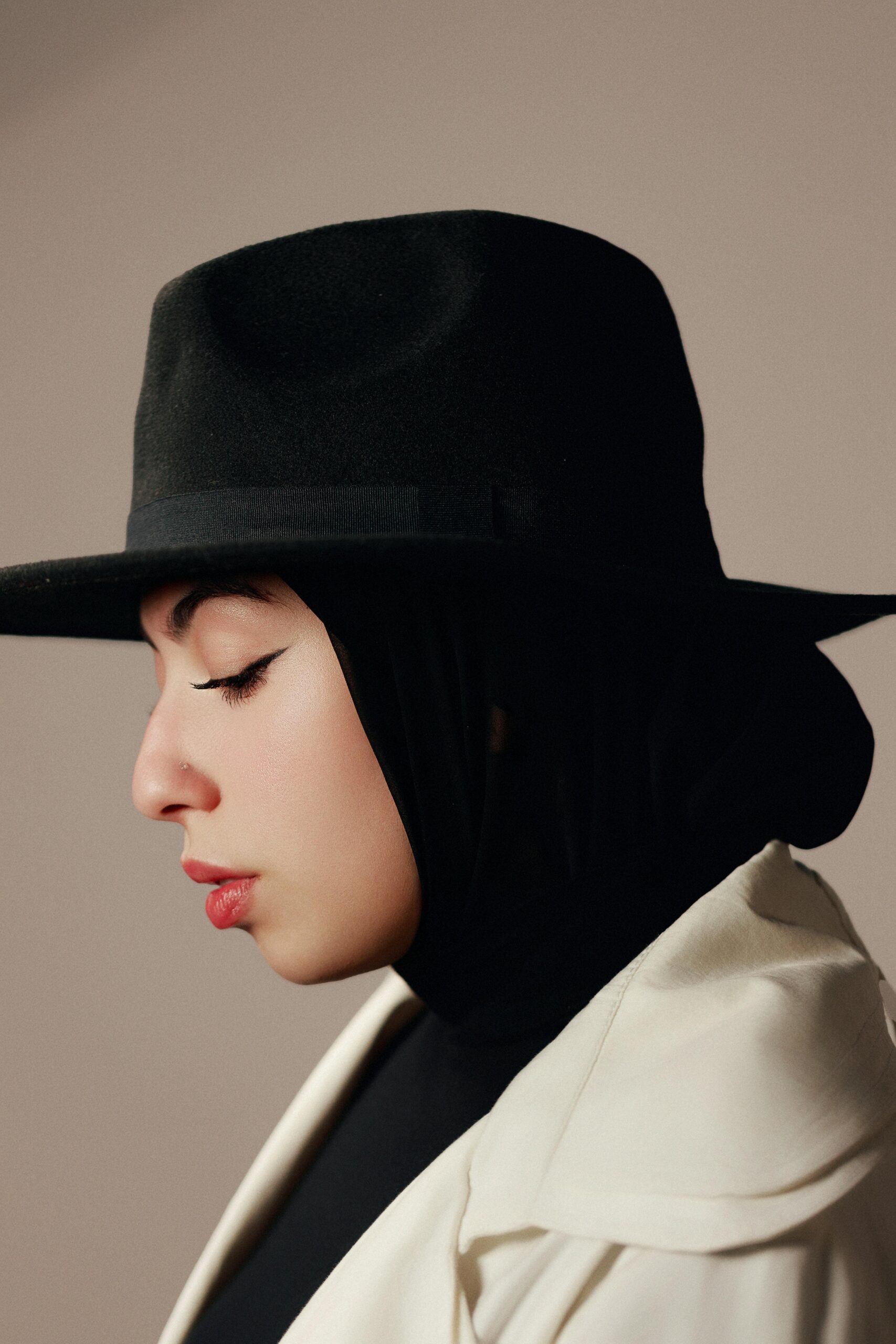 Elegancki portret kobiety w hidżabie i kapeluszu z szerokim rondem, emanujący wyrafinowaniem.