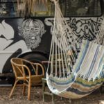 Tajemnice Starożytnej Cypru: Opowieść o Afrodycie i Innych Mitach Kolorowy hamak obok pokrytego graffiti pojazdu z rustykalnymi meblami tworzy wyjątkową scenerię na świeżym powietrzu.