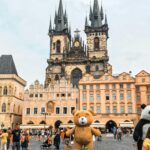 Zamki w Czechach godzinę od polskiej granicy - niesamowite, zachwycające, magiczne a tak blisko! Odwiedzający cieszą się praskim rynkiem Starego Miasta z katedrą św. Wita i zabawnymi maskotkami na pierwszym planie.