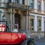 Pardubice, miasto pachnące piernikiem – Co warto zobaczyć? Uroczy, zabytkowy czerwony samochód zaparkowany przed zabytkowym budynkiem w Pradze, Czechy.