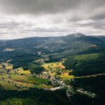 Zapierające dech w piersiach zdjęcie lotnicze przedstawiające bujne pola i góry Malá Úpa w Czechach.