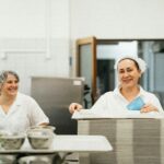 Przyjazny personel stołówki pracujący razem w kuchni, pokazujący pracę zespołową i obsługę.