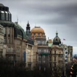 Dramatyczny widok na historyczne budynki Pragi pod zachmurzonym niebem, ukazujący architektoniczną elegancję.
