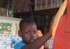 Młody chłopak w niebieskim stroju korzystający ze staromodnego automatu telefonicznego w Santo Domingo na Dominikanie.