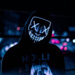 Dominikana – jak uniknąć pułapek turystycznych? Osoba ubrana w świecącą neonową maskę z kapturem w nocnej scenerii miejskiej, Dominikana.